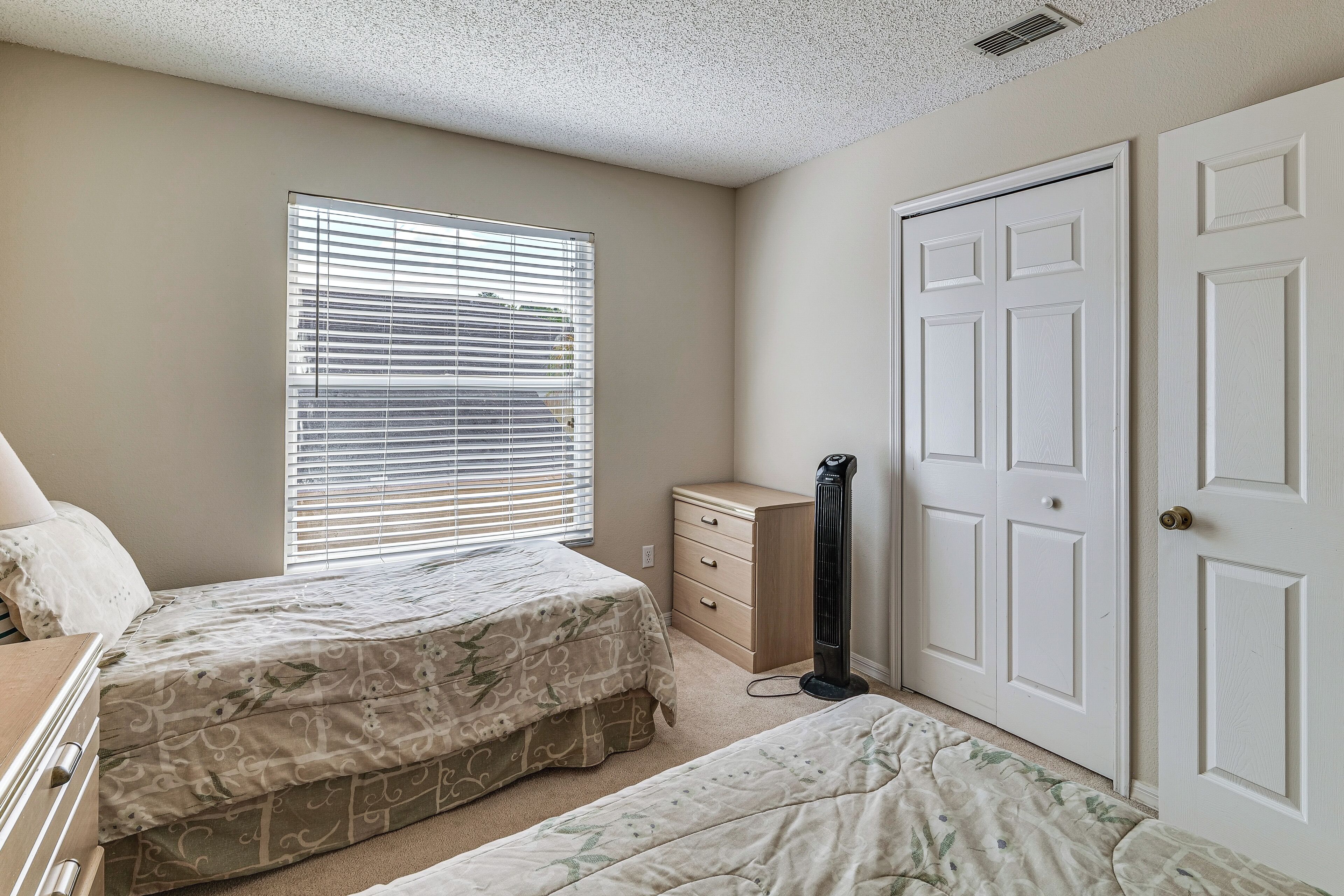Une chambre avec deux lits, une commode, un radiateur et un placard.