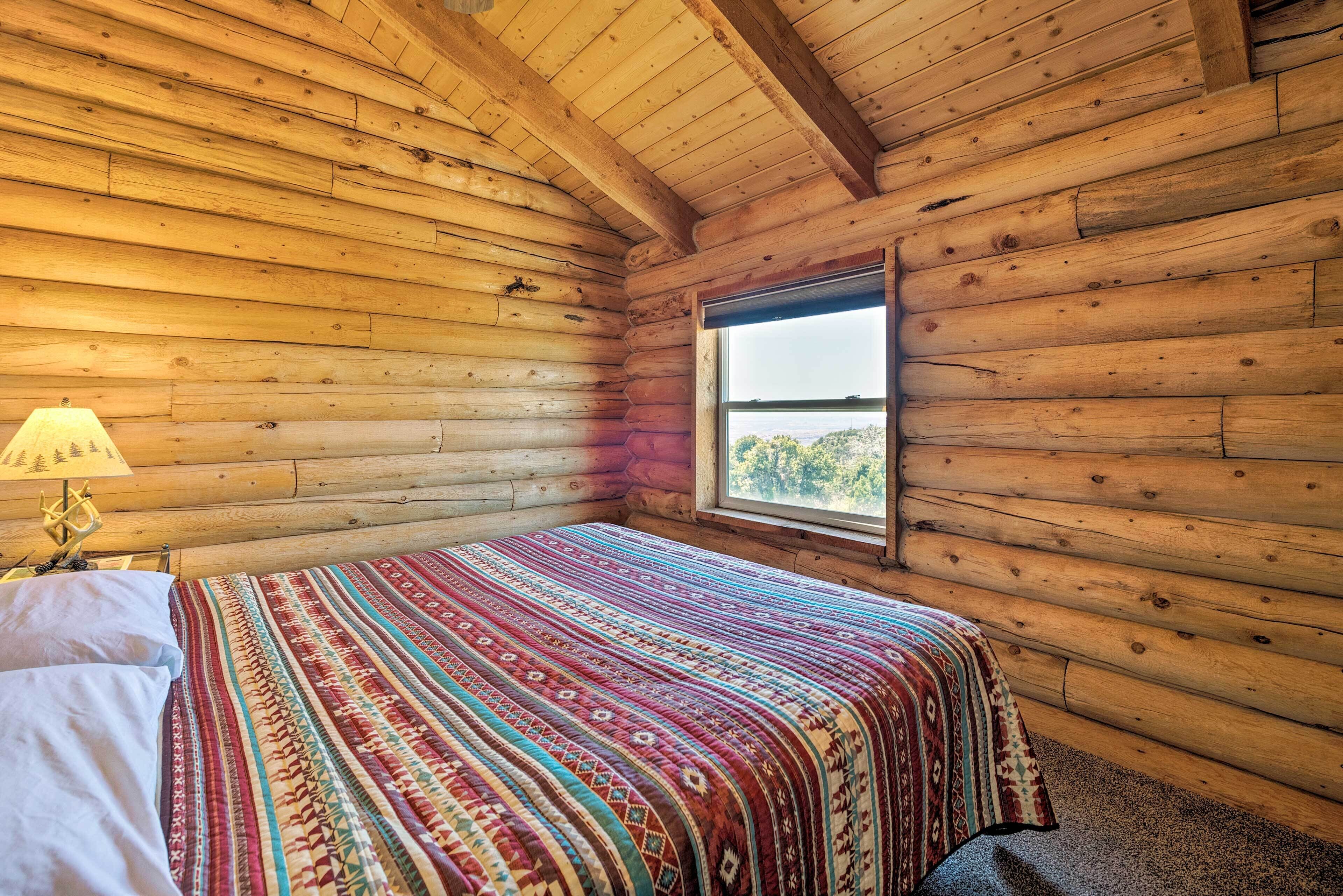 Una habitación tipo cabaña de madera con cama, ventana y lámpara.