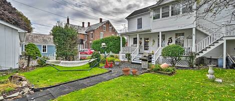 A residential neighborhood with houses, a grassy yard, a hammock, and a small garden.