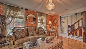 A spacious living room with a leather sofa, a coffee table, and a chandelier. - Unique & Historic Home Walk to Lake Champlain (Plattsburgh)