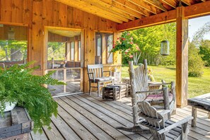 A wooden deck with outdoor furniture, including chairs and a table, overlooking a garden. - Porch & Countryside Views! Greensboro Home (Stannard)