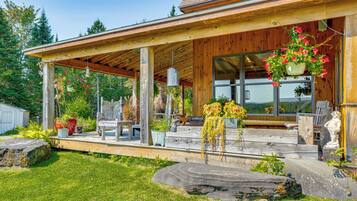 A wooden covered porch with outdoor seating, potted plants, and a stone sculpture.