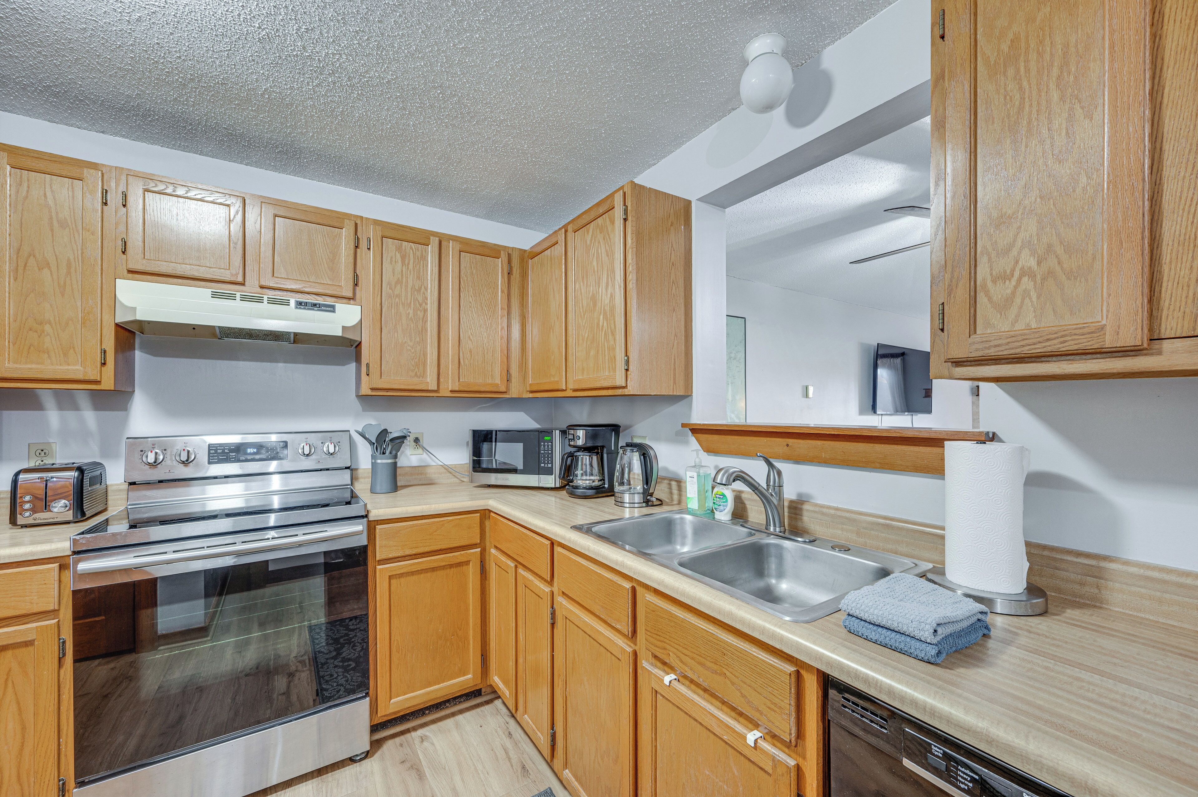 A kitchen with wooden cabinets, stainless steel appliances, a microwave, a coffee maker, and a dishwasher.