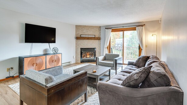 Ein Wohnzimmer mit Kamin, Flachbildfernseher, Sofa und Couchtisch.