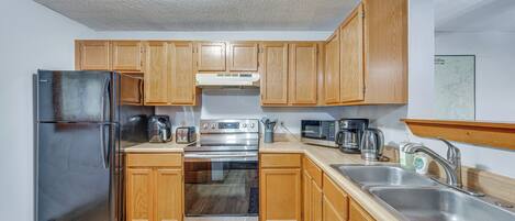 A modern kitchen with wooden cabinets, stainless steel appliances, and a double sink.
