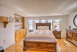 Un dormitorio con una cama de madera, estanterías empotradas, un reloj y una ventana con cortinas de encaje.
