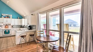 A kitchen with white cabinets, a wooden island, and a dining area with a table and chairs. - Walk to Ocean: Coastal Home in Crystal Beach! (Port Bolivar)