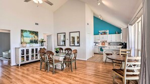 A spacious kitchen with white cabinets, a dining area with wooden chairs, and a teal accent wall. - Walk to Ocean: Coastal Home in Crystal Beach! (Port Bolivar)