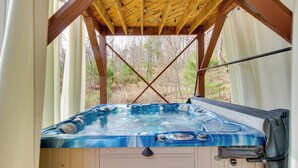 A hot tub under a wooden pergola with a view of a forested area. - Broadway Cabin w/ Hot Tub: Hike & Ski (Broadway)