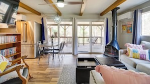 A cozy living room with a fireplace, a dining area, and a kitchen with a refrigerator. - Broadway Cabin w/ Hot Tub: Hike & Ski (Broadway)