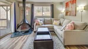 A living room with a fireplace, a sofa, and a painting on the wall. - Broadway Cabin w/ Hot Tub: Hike & Ski (Broadway)