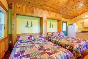 Ein Zimmer mit zwei Betten, Holzwänden, einem Fenster, einer Mikrowelle und einer Uhr.