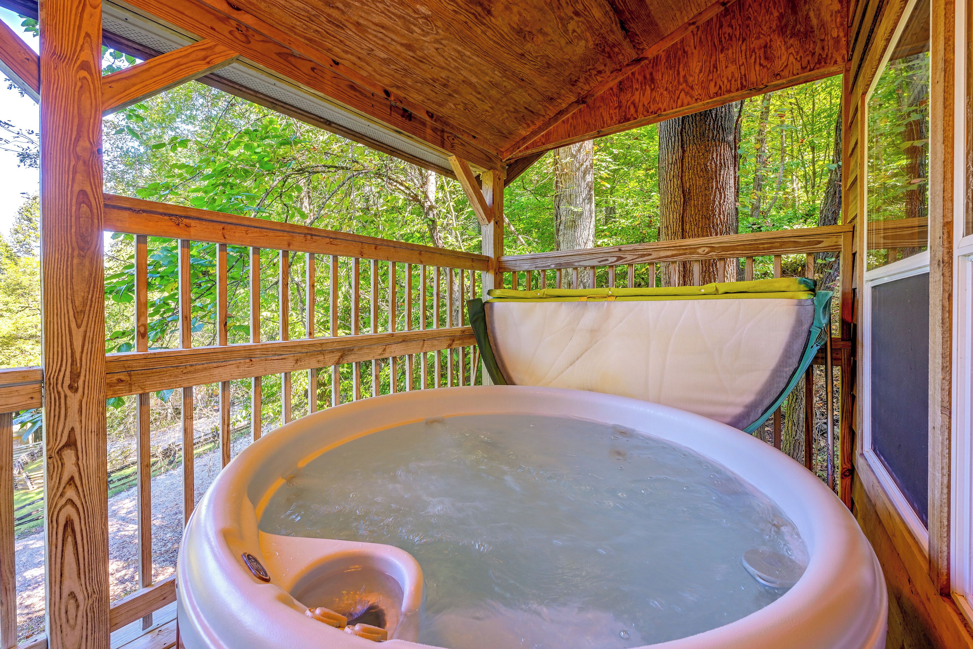 Un jacuzzi en un pabellón de madera con vista a un bosque.