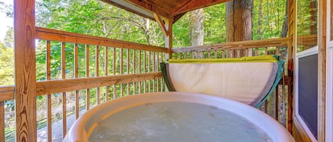 Un jacuzzi en un pabellón de madera con vista a un bosque.