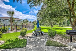 A patio area with a table and chairs, a barbecue grill, and a pool in the background. - Steps to Pool: Myrtle Beach Vacation Rental! (Myrtle Beach)