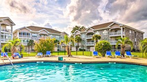 A swimming pool with lounge chairs and a building with balconies. - Steps to Pool: Myrtle Beach Vacation Rental! (Myrtle Beach)