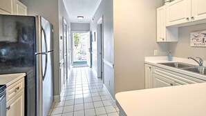 A narrow kitchen with white cabinets, a stainless steel refrigerator, and a sink. - Steps to Pool: Myrtle Beach Vacation Rental! (Myrtle Beach)