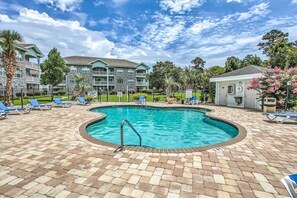 A swimming pool with a brick deck, surrounded by lounge chairs and a building with balconies. - Steps to Pool: Myrtle Beach Vacation Rental! (Myrtle Beach)