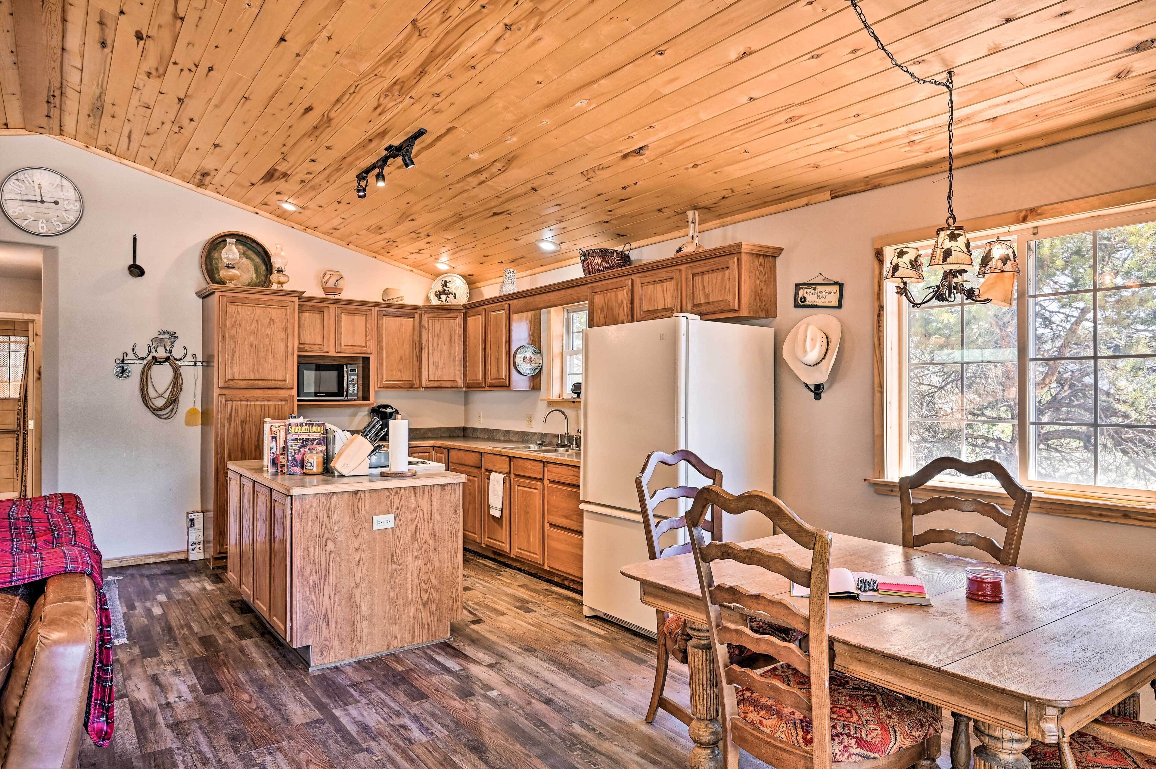 A rustic kitchen with wooden cabinets, a central island, and a dining table with chairs.