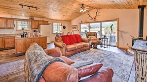 A spacious living area with a fireplace, a cozy fireplace area, and a large window offering a view of the outdoors. - 4-season Mountain Escape With Breathtaking View! (Coaldale)