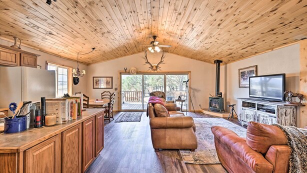 A spacious living area with a wooden ceiling, a large sofa, a television, and a fireplace. - 4-season Mountain Escape With Breathtaking View! (Coaldale)