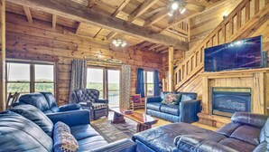 A log cabin interior with leather sofas, a fireplace, and a large TV. - Spacious Cabin on Dale Hollow Lake w/ Hot Tub! (Albany)