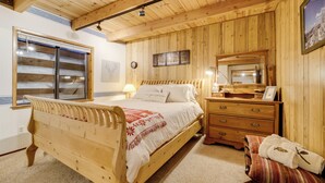 Ein Schlafzimmer aus Holz mit einem Bett, einem Schminktisch, einem Spiegel und einem Fenster.