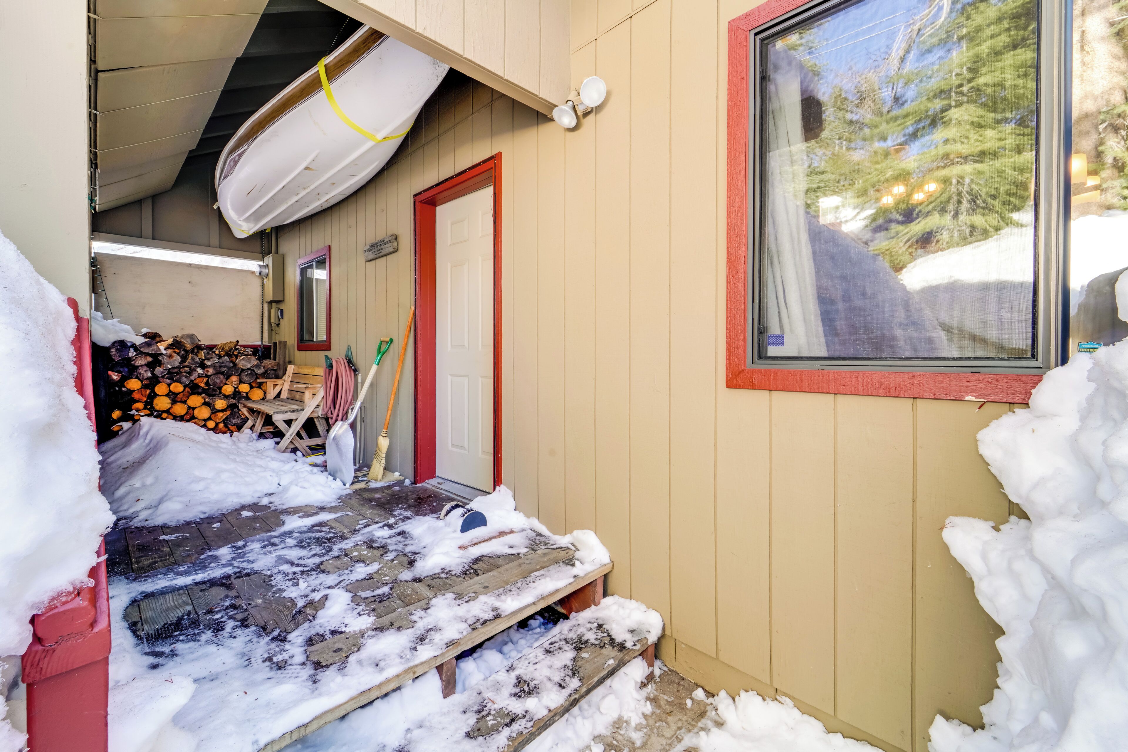A wooden cabin with a window, a door, and a pile of firewood.