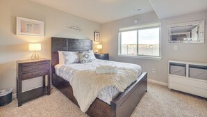 Une chambre à coucher avec un grand lit, deux tables de chevet, une commode, une fenêtre donnant sur un beau paysage et un miroir décoratif.