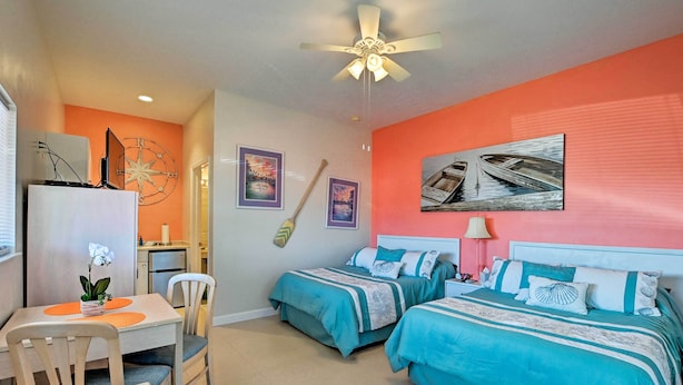 A room with two beds, a dining table, and a ceiling fan. - Everglades Studio W/marina View, Patio+pool Access (Naples)