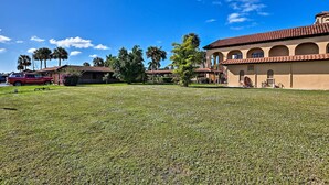 A building with a tiled roof and arched windows, surrounded by a well-maintained lawn and palm trees. - Everglades Studio W/marina View, Patio+pool Access (Naples)