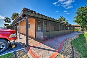 A building with a tiled roof and large windows, a paved walkway, and a parked red vehicle. - Everglades Studio W/marina View, Patio+pool Access (Naples)