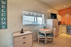 A compact kitchen with a dining area, a white refrigerator, a TV on top, and a "WELCOME" sign on the wall. - Everglades Studio W/marina View, Patio+pool Access (Naples)