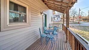 A wooden deck with a table and chairs, a covered porch, and a house with a green door. - Calico Rock Home, Walk to White River & Dtwn! (Calico Rock)