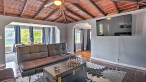 A spacious living room with a leather sofa, a vintage suitcase coffee table, and a ceiling fan.