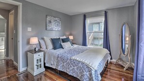 A bedroom with a bed, nightstand, dresser, and a large mirror.