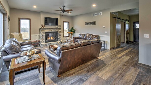 A spacious living room with a fireplace, leather sofas, and a dining area. - Lakefront Wisconsin Dells Home w/ Game Room (Wisconsin Dells)