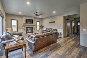 A spacious living room with a fireplace, leather sofas, and a dining area. - Lakefront Wisconsin Dells Home w/ Game Room (Wisconsin Dells)