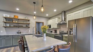 A modern kitchen with a central island, stainless steel appliances, and a hanging light fixture. - Lakefront Wisconsin Dells Home w/ Game Room (Wisconsin Dells)