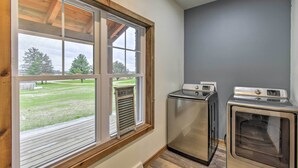 A laundry room with two washing machines, a window with a view of a grassy area, and a wooden ceiling. - Lakefront Wisconsin Dells Home w/ Game Room (Wisconsin Dells)