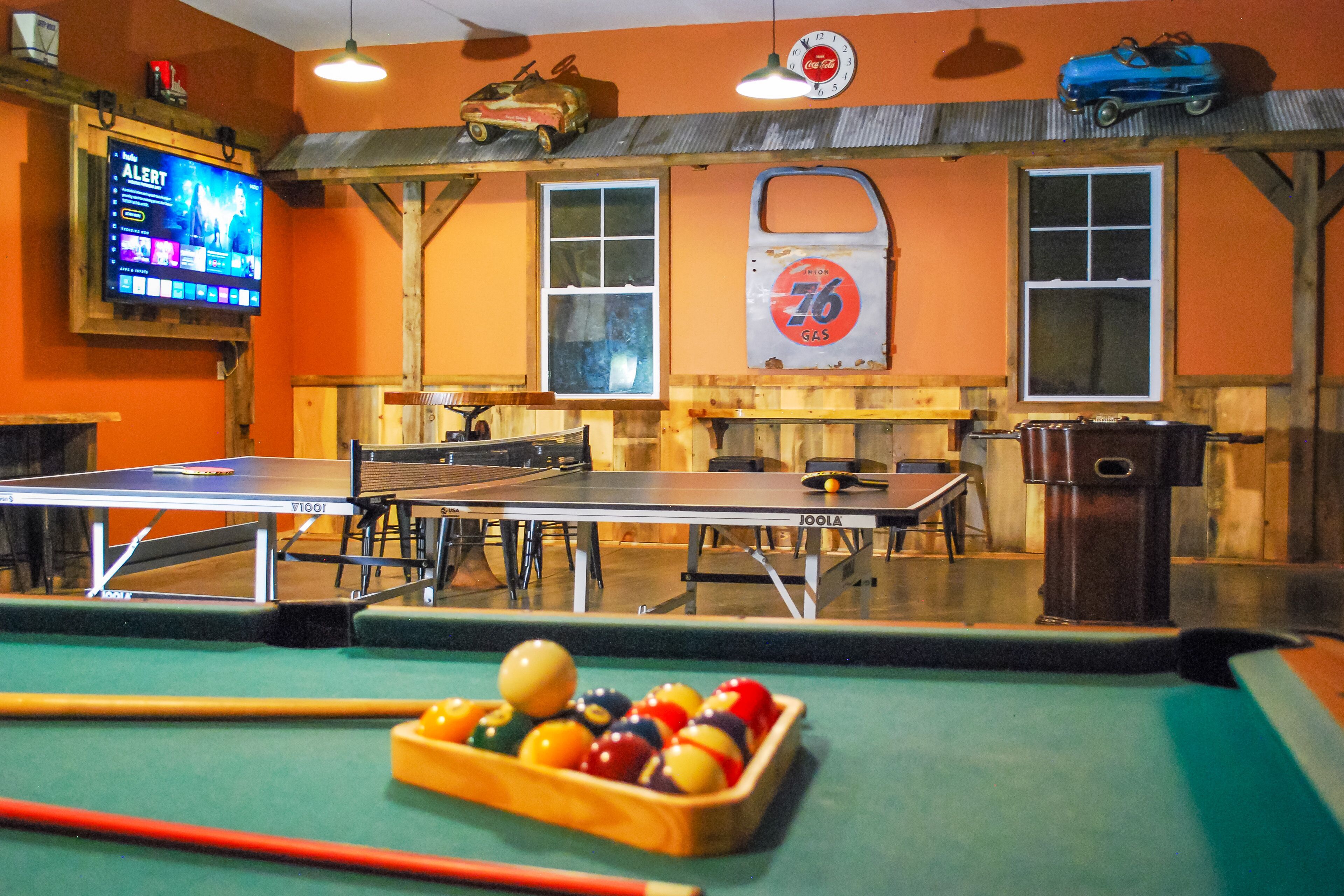 A billiards room with a pool table, a table tennis table, and a billiard cue rack.