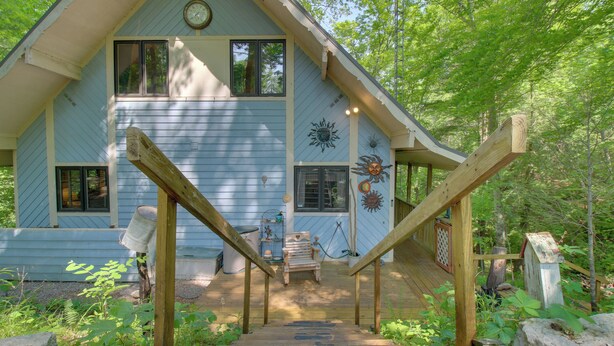 A wooden staircase leading to a house with a blue exterior, a clock on the wall, and a sun decoration.