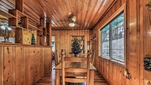 Un interior de fusta amb una zona de menjador, un arbre de Nadal i una finestra gran.