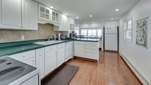 A modern kitchen with white cabinets, a granite countertop, and a wooden floor. - Lakefront Michigan Cottage - Deck, Grill & Kayaks! (Sturgis)