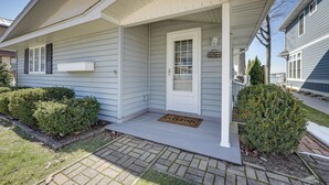 A house with a front porch, a welcome mat, and a small garden area. - Lakefront Michigan Cottage - Deck, Grill & Kayaks! (Sturgis)