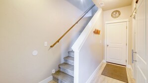 Eine Treppe mit hölzernem Geländer, eine weiße Tür mit einem kreisförmigen Emblem und eine Fußmatte.