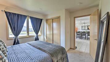 A bedroom with a bed, a wardrobe, and a view of a dining area.