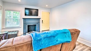 A living room with a fireplace, a sofa, a table, and a door.