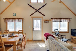 Una sala de estar acogedora con techo de madera, un sofá, televisor y un comedor con mesa y sillas.