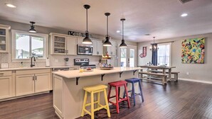 A spacious kitchen with a central island, pendant lighting, and a dining area with a bench. - Cozy Retreat w/ Hot Tub & Fire Pit: Close to Main! (Fredericksburg)